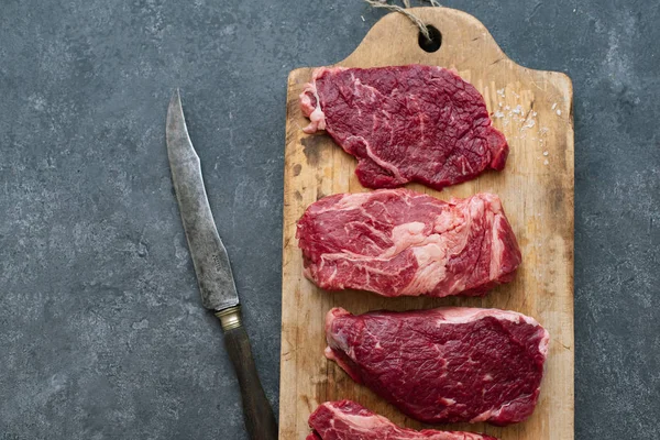 Vintage kesme tahtası üzerinde Ham siyah angus prime sığır eti biftek çeşitli 