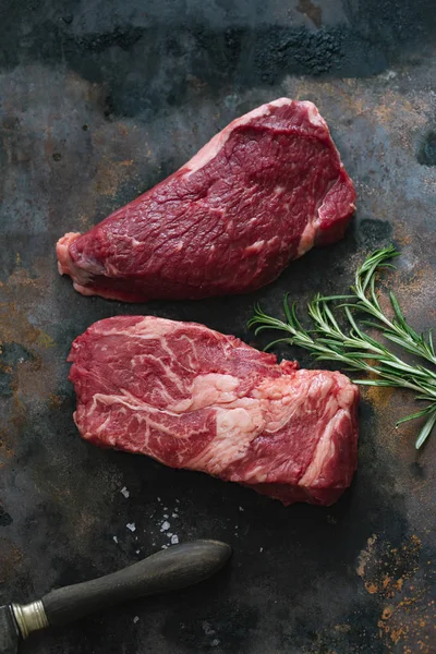 Koyu arka plan üzerinde bıçak ile biberiye ve deniz tuzu ile Çiğ siyah angus prime sığır biftek 