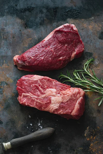 Koyu arka plan üzerinde bıçak ile biberiye ve deniz tuzu ile Çiğ siyah angus prime sığır biftek 