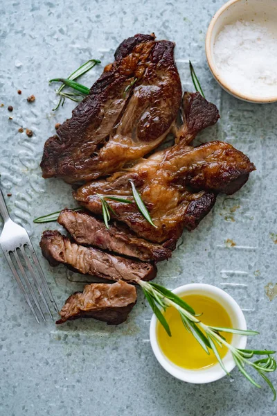 Pişmiş siyah angus prime sığır eti biberiye ve metalik tepsiüzerinde zeytinyağı ile kase ile