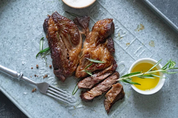 Pişmiş siyah angus prime sığır eti biberiye ve metalik tepsiüzerinde zeytinyağı ile kase ile