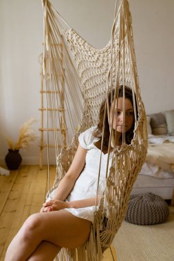 Evde asılı hamak sandalye otururken genç Redhead kadın rahatlatıcı