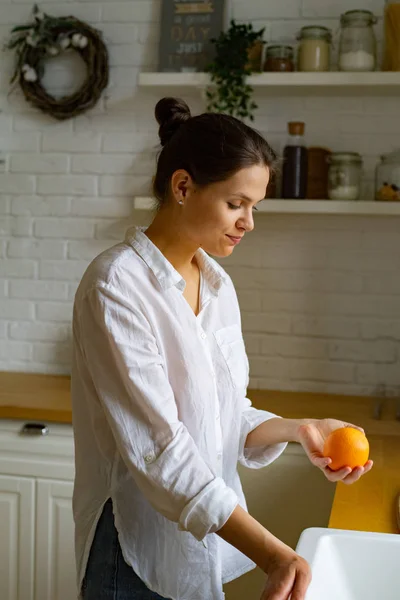 Młoda Kobieta Trzyma Świeży Pomarańczowy Stojąc Kuchni — Zdjęcie stockowe