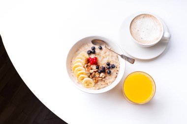 Masada portakal suyu bardağı ile çilek ve kahve fincanı ile yulaf ezmesi ile kahvaltı 