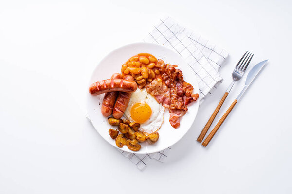 классический английский завтрак с жареным беконом и грибами с яйцами, подаваемыми на белой тарелке
 