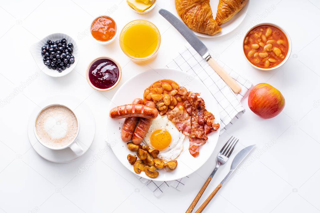 fried bacon with mushrooms and egg on plate served with orange juice and coffee with croissants on white table, classical english breakfast concept 