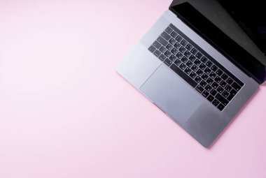 pembe arka planda gri dizüstü bilgisayar açıldı. Üst görünüm, blogger işyeri konsepti 