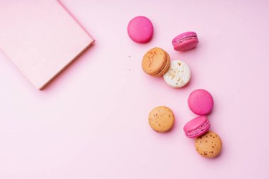 pembe arka plan üzerinde tatlı renkli macaroons ve not defteri. Üstte görüntü