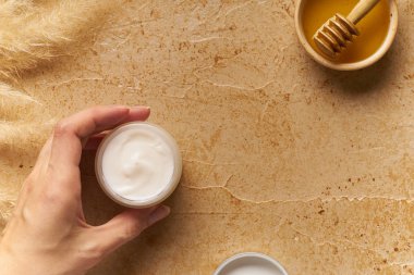 Spa güzellik cilt bakımı krem küçük bir konteyner tutan kadın el ile traverten arka plan üzerinde alay. Üstte görüntü 