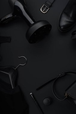 Siyah monokromatik kıyafetler ve esmer arka planda güzellik ekipmanları olan aksesuarlar. Kara Cuma satış konsepti 