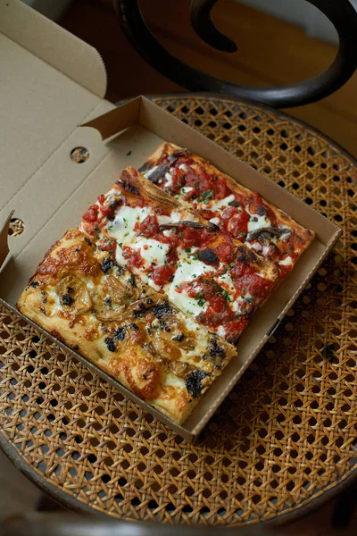 Rectangular slices of rustic pizza with toppings and flavors in carton box