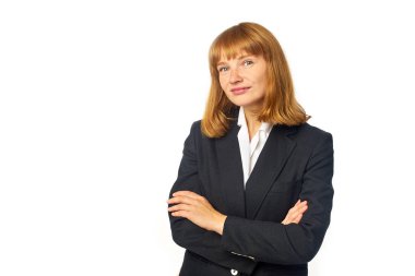 İş elbiseli kızıl saçlı kadın beyaz arka planda kollarını kavuşturmuş poz veriyor.
