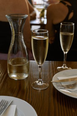 İki kadehte köpüklü şarap ve ahşap masada kavanoz, yakın görüş. 