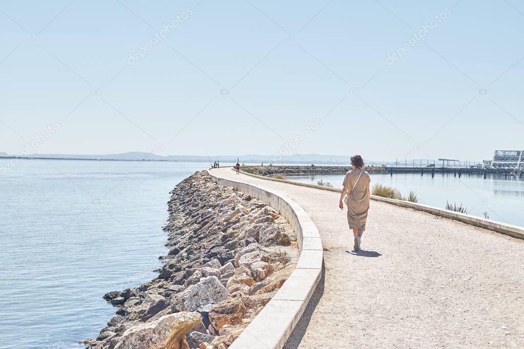 Young woman walking at Tagus river shore near Vasco da Gama bridge