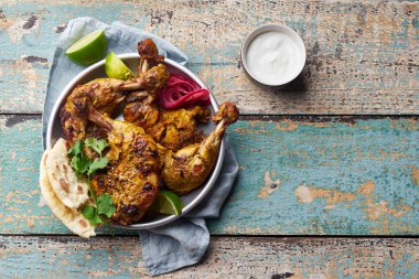 Tikka 'da terbiye edilmiş Tandır tavuğu pirinç naan ve limonlu sade yoğurt ve ahşap zemin üzerinde kişniş ile servis edilir. Hint mutfağı konsepti 