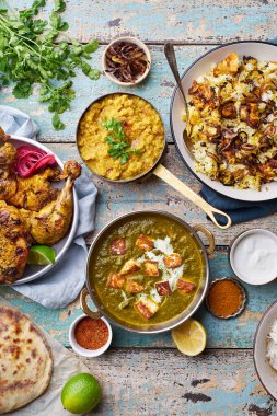 Hint mutfağında, biryani ve kırmızı körili tandır tavuğu pilav naan ve ahşap arka planda basmati pilavlı palak paneer.