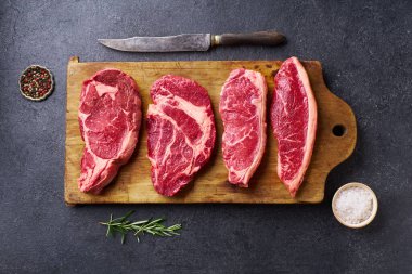 Tahtayı pirzola ve striploin ve picanha ve chuck rulo taze siyah angus ana çiğ biftek ahşap arka planda, üst görünüm