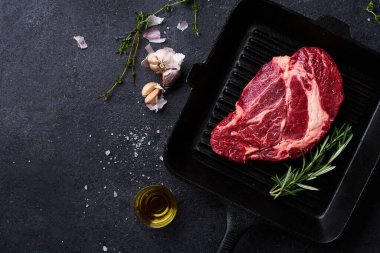 Siyah Angus bifteği dökme demir ızgara tavada taze biberiye ve sarımsaklı zeytinyağı. Yemek malzemeleriyle yaratıcı düzen, Üst Görünüm