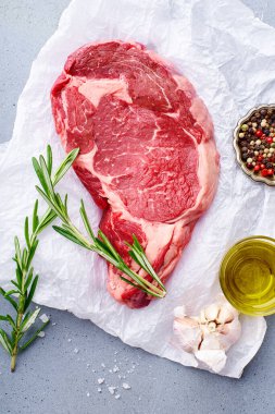 Siyah Angus bifteği parşömen kağıdında barbekü için hazır, biberiyeli ve zeytinyağlı sarımsaklı. 