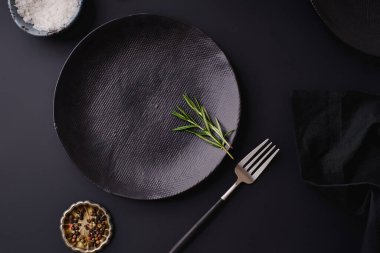 black empty plates with fork and rosemary on dark background, Dinner setting template