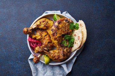 Tikka 'da terbiye edilmiş Tandır tavuğu pirinç naan ve limonla servis edilmiş, sade yoğurt ve mavi arka planda kişniş. Hint mutfağı konsepti 