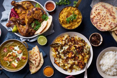 Hint mutfağında, biryani ve kırmızı körili mercimek dalıyla tandır tavuğu ve pirinç naan ile palak paneer ve mavi arka planda basmati pilavı.
