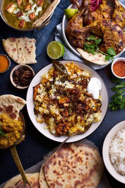 Hint mutfağında, biryani ve kırmızı körili mercimek dalıyla tandır tavuğu ve pirinç naan ile palak paneer ve mavi arka planda basmati pilavı.