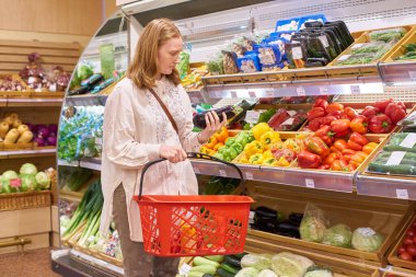 Sarı saçlı genç bir kadın süpermarketten alışveriş yapıyor.