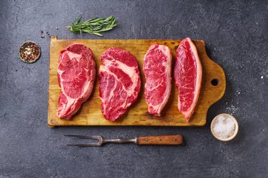 Tahtayı pirzola ve striploin ve picanha ve chuck rulo taze siyah angus ana çiğ biftek ahşap arka planda, üst görünüm