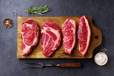 Tahtayı pirzola ve striploin ve picanha ve chuck rulo taze siyah angus ana çiğ biftek ahşap arka planda, üst görünüm