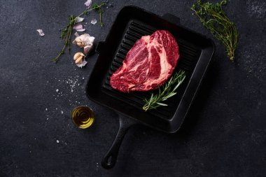 Siyah Angus bifteği dökme demir ızgara tavada taze biberiye ve sarımsaklı zeytinyağı. Yemek malzemeleriyle yaratıcı düzen, Üst Görünüm