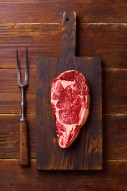 Tahta üzerinde siyah angus bifteği ve ahşap arka planda biftek, üst manzara. 
