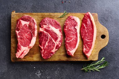 Tahtayı pirzola ve striploin ve picanha ve chuck rulo taze siyah angus ana çiğ biftek ahşap arka planda, üst görünüm