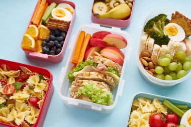 Üst görünüm ofis beslenme çantaları. Mavi arka planda çeşitli sağlıklı yemekler.