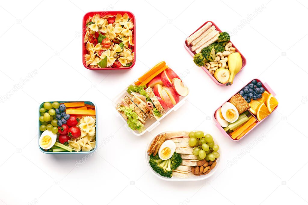 Top view of office lunchboxes with various healthy nutritious meals on white background. Lunch food from above
