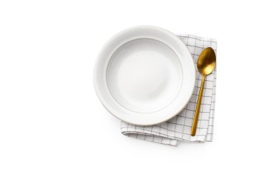 Düz beyaz tabak ve beyaz arka planda kareli peçeteli altın kaşık vardı. Üst görünüm 