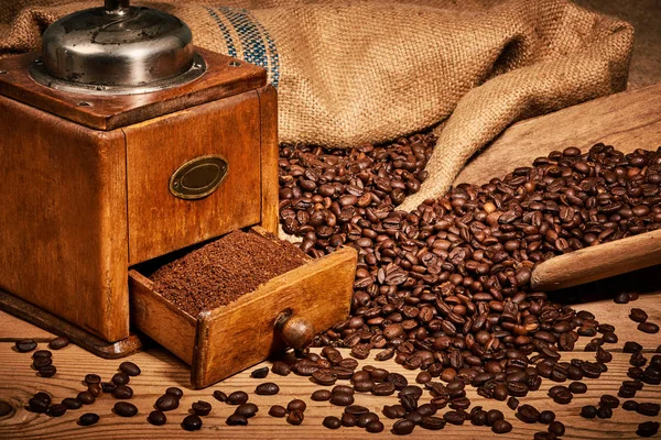 Coffee with old coffee grinder and beans on wooden table