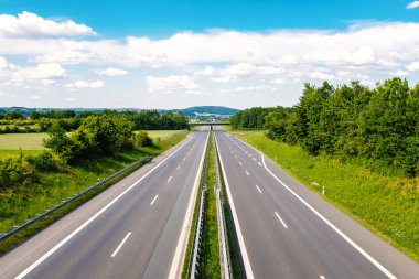 Bulutların üstünde mavi bir gökyüzü ile yeşil bir manzara ile boş Otoban