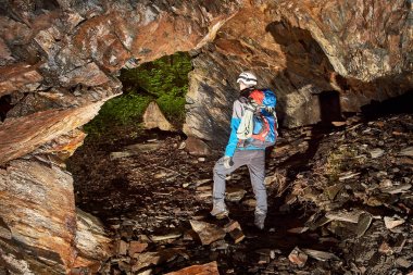 Young speleologist exploring a cave clipart