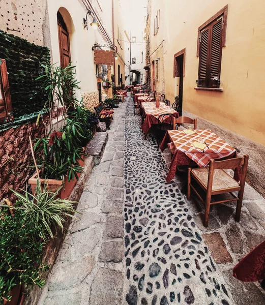 Picturesque narrow alley with tables and chairs in old town Castelsardo, Italy