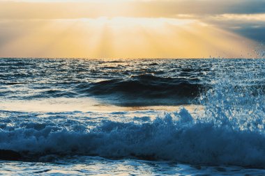Gün batımında parlayan bir güneş altında küçük dalgaların kapat