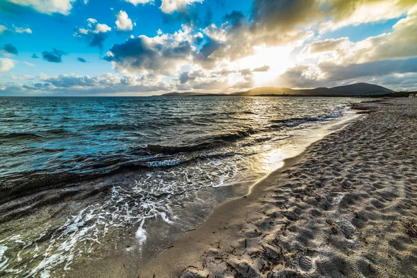 Rivage sablonneux sous un ciel nuageux au coucher du soleil — Photo