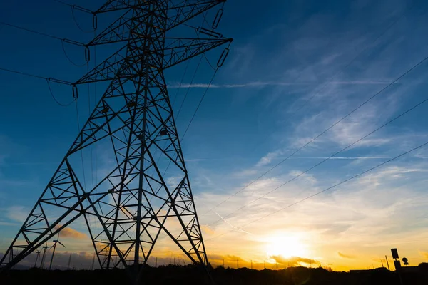 Eletricidade pilão sob um céu colorido ao pôr-do-sol — Fotografia de Stock