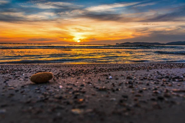 Småsten anad sand på stranden vid solnedgången — Stockfoto
