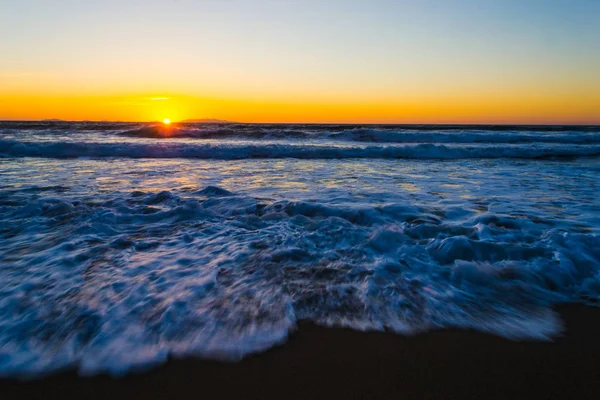 Fale przy brzegu o zachodzie słońca w ruchu efekt rozmycia — Zdjęcie stockowe