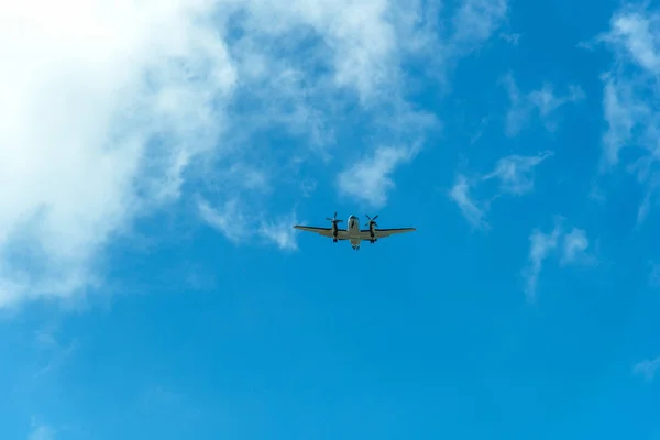 Kaksoispotkurikone lentää sinisellä taivaalla pilvien kanssa — kuvapankkivalokuva