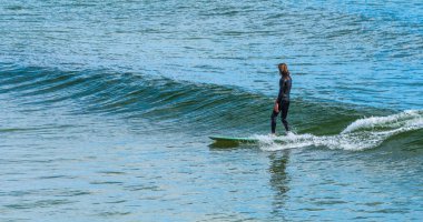 Sörfçü bir longboard üzerinde küçük bir dalga sörf