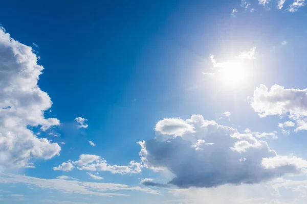 Солнце светит в голубом небе с белыми облаками — стоковое фото