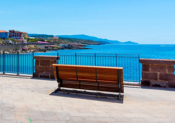 stock image Wooden bench in Alghero seafront on a clear day