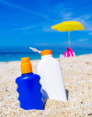 Yazın beyaz bir sahilde mavi ve beyaz bronz şişeler